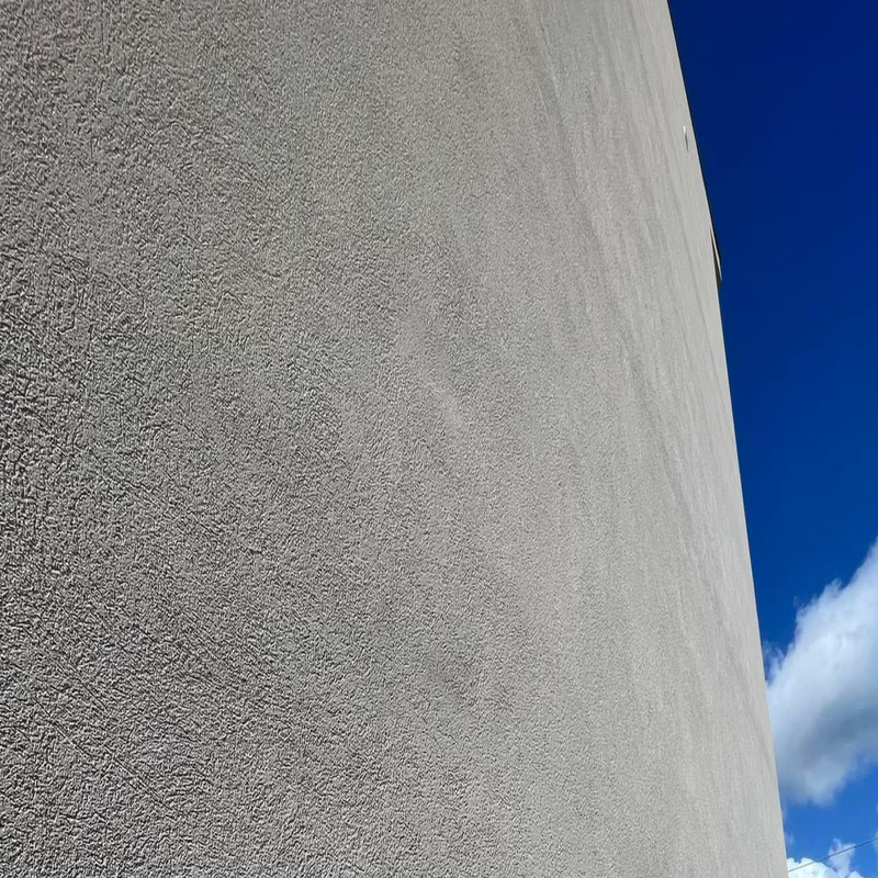 Close-up view of a textured lime-based wall finish against a clear blue sky.