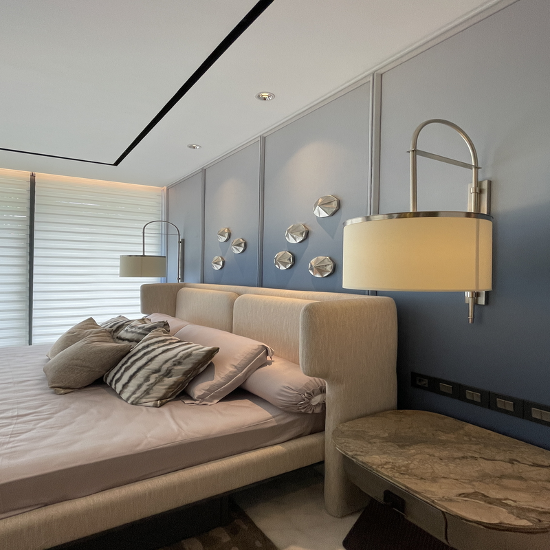 Luxurious modern bedroom with a plush upholstered bed, elegant wall sconces, and a blue accent wall with metallic decor.